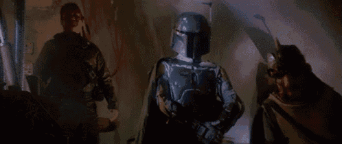 a man in a blue helmet is standing in a dark room with other men .