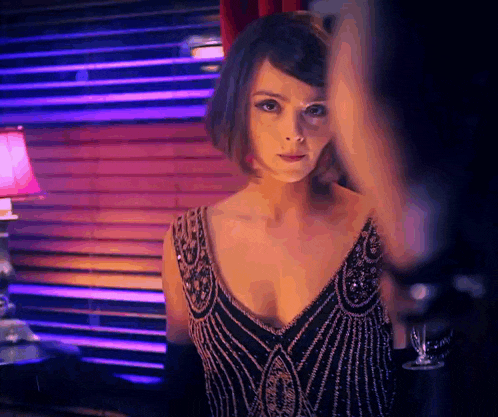 a woman in a black dress stands in front of a window