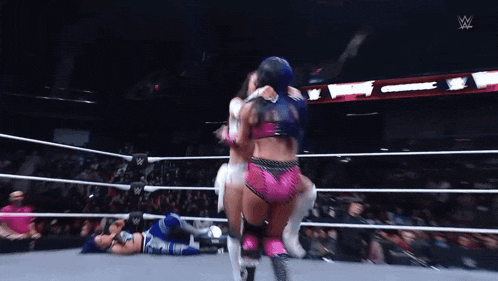 two women are wrestling in a wrestling ring and one of them is hugging the other .