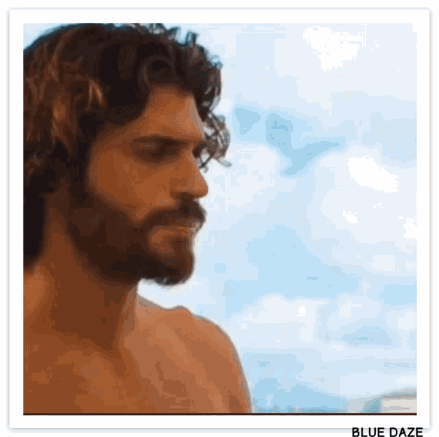 a shirtless man with curly hair and a beard is looking at the camera .