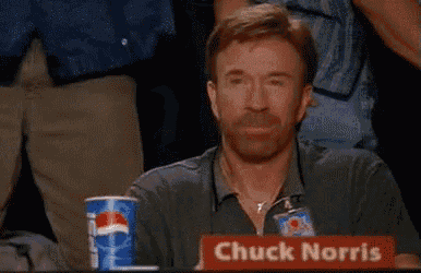 a man sitting at a table with a sign that says chuck norris