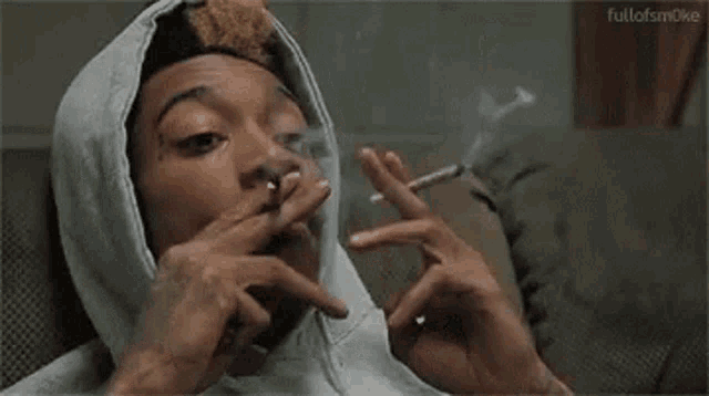 Gif of a guy in a green hoodie smoking two joints back and forth