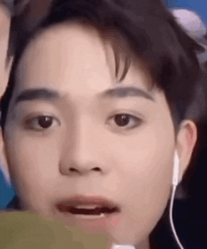 a close up of a young man 's face with earphones on .