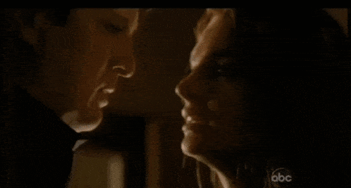 a man and a woman are looking at each other in a dark room on a television screen .