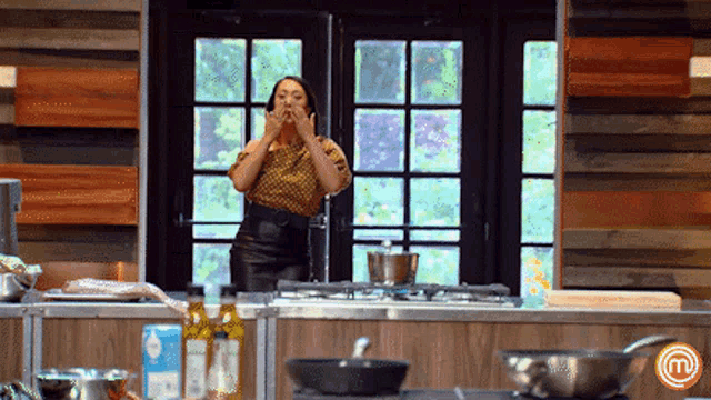 a woman is standing in front of a kitchen counter with a m logo on it