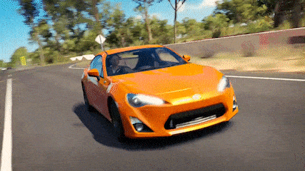 an orange car is driving down a road with trees on the side
