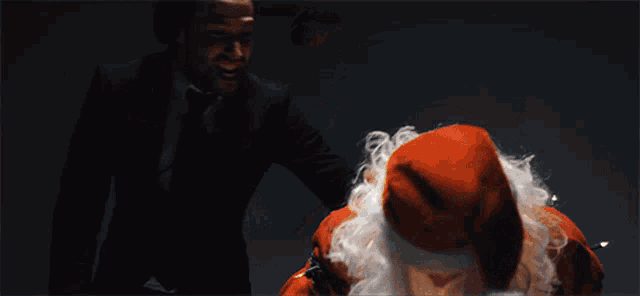 a man in a suit is standing next to a man in a santa costume