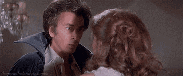 a man and a woman are looking into each other 's eyes in a room .