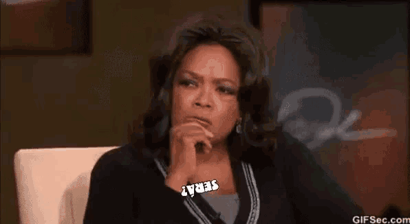 oprah winfrey is sitting in a chair with her mouth open while holding a sign that says sera .