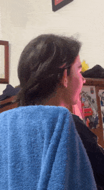 a person with a blue towel on their shoulder with a picture of a man on the wall behind them