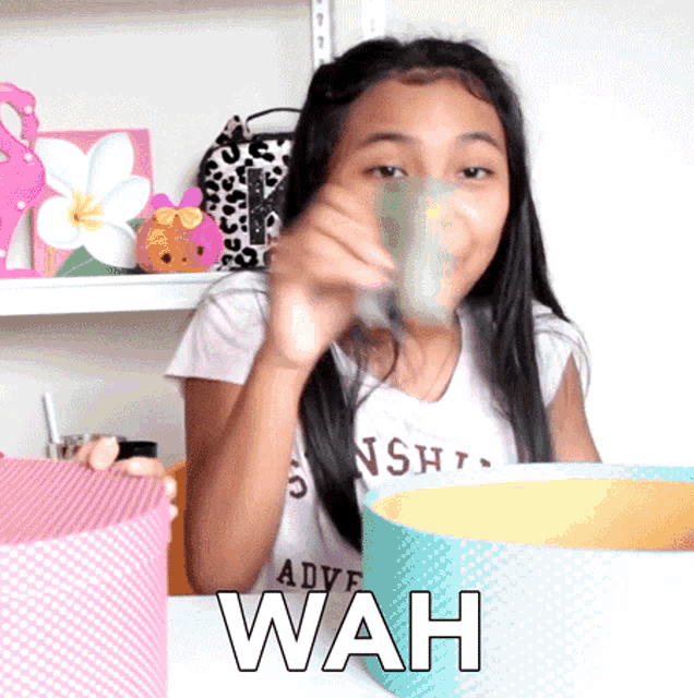 a young girl sitting at a table with the word wah on it