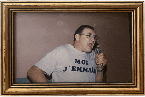 a man singing into a microphone while wearing a shirt that says moi j'emmau