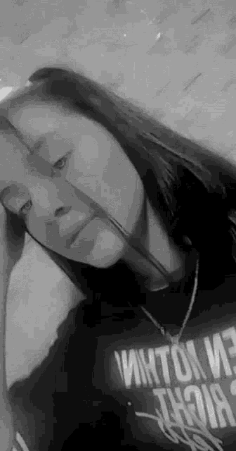 a black and white photo of a girl wearing a necklace and a t-shirt with the word nirvana on it .
