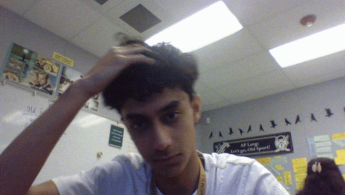 a young man in a classroom with a sign on the wall that says ap long let 's go old sport