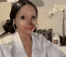 a woman is applying lipstick to her lips while wearing a white robe .