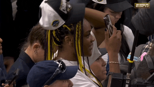 a woman taking a picture with her phone with the espn logo visible
