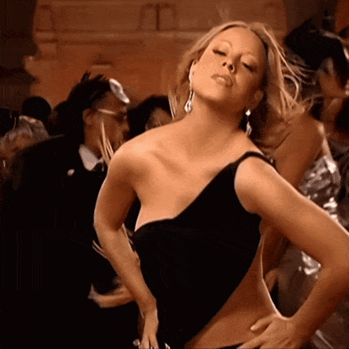 a woman in a black dress is dancing in front of a crowd of people