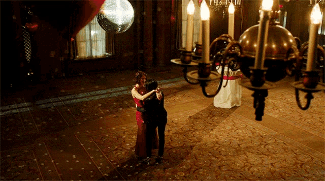 a man and a woman are dancing in a room with candles and balloons