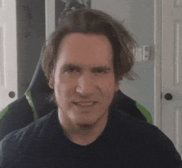 a man in a black shirt is smiling in front of a green chair