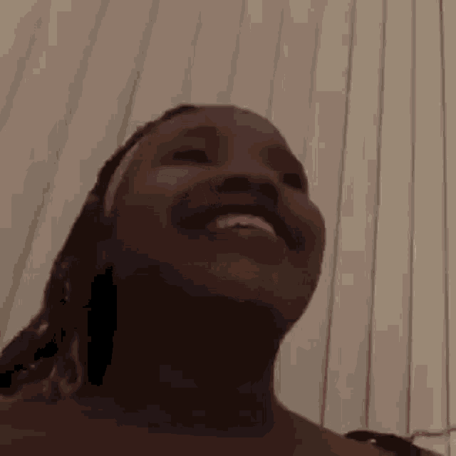a close up of a woman smiling in front of a white curtain .