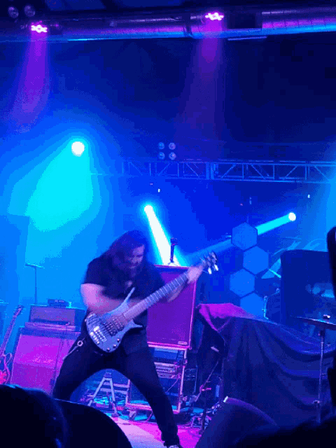a man playing a guitar on a stage with blue lights behind him