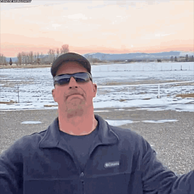 a man wearing sunglasses and a columbia jacket is standing in a snowy field
