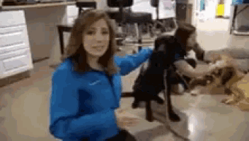 a woman in a blue nike jacket is petting a dog .