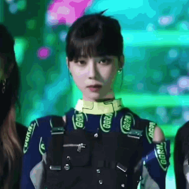 a woman in a blue and black outfit is standing in front of a crowd and looking at the camera .