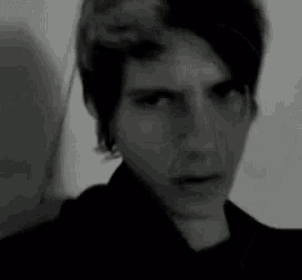 a black and white photo of a young man 's face looking at the camera .