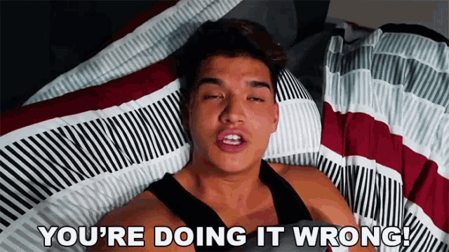 a man laying on a bed with the words you 're doing it wrong above him
