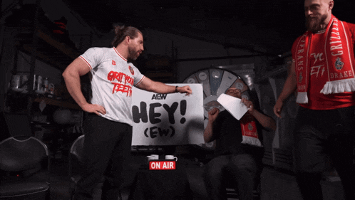 two men holding a sign that says hey on it