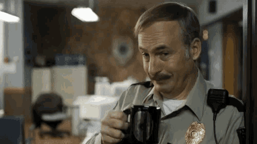 a man in a sheriff 's uniform is holding a cup of coffee