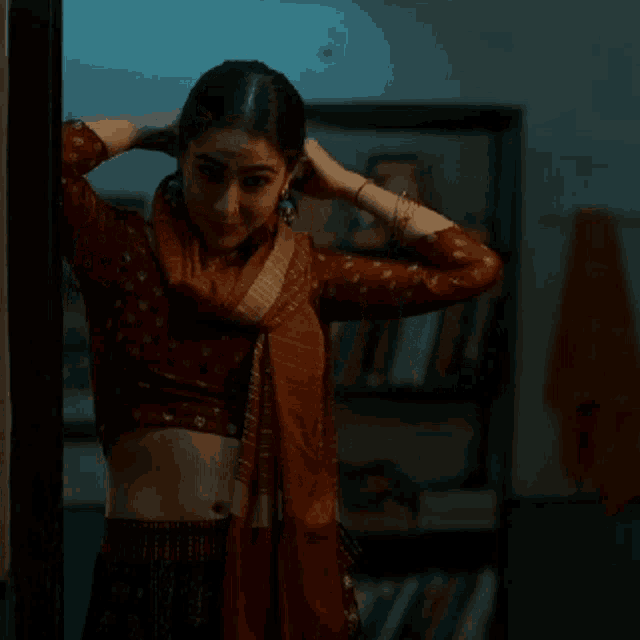 a woman adjusts her earring while standing in a dark room