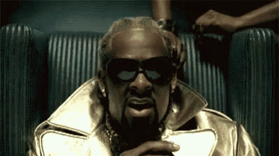 a man wearing sunglasses and a gold jacket is sitting in a chair