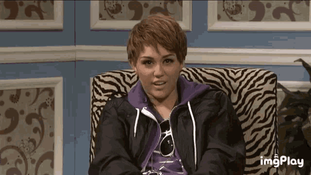 a woman is sitting in a chair with a zebra print on it and the words imgplay on the bottom left