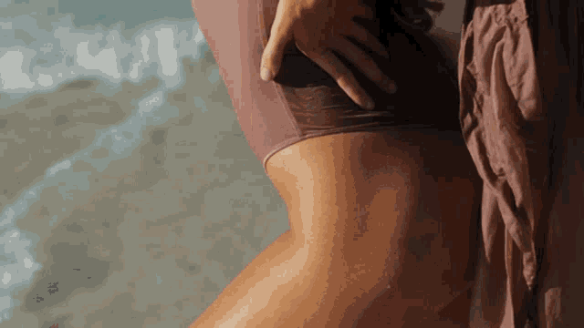 a woman in a swimsuit is standing on a beach