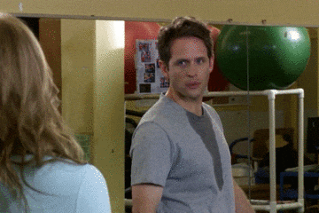 a man in a grey shirt stands in front of a green ball