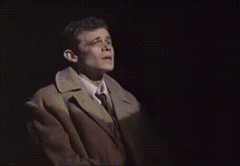 a man in a suit and tie is standing in front of a black background .