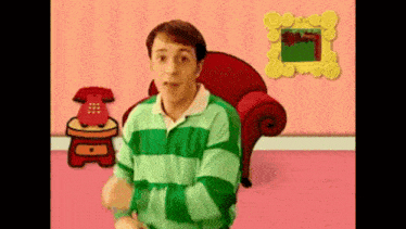 a man in a green and white striped shirt is standing in a pink room