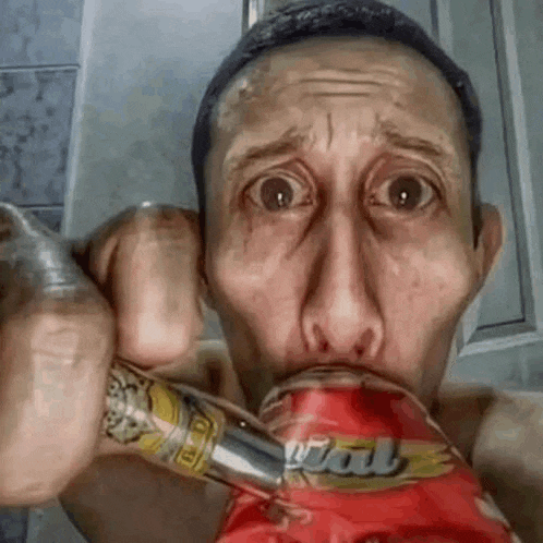 a man is holding a can of soda in his mouth and making a funny face .