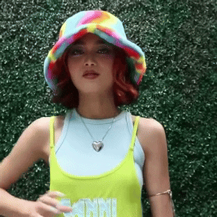 a woman wearing a colorful hat and a tank top that says mini