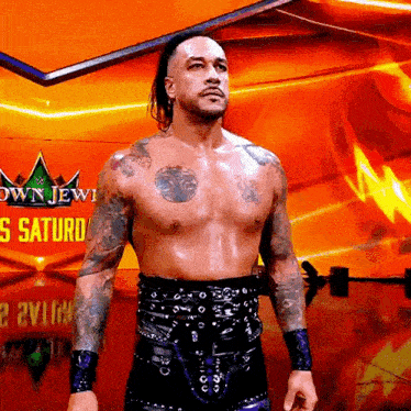 a shirtless wrestler is standing in front of a sign that says crown jewel saturday