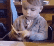 a little boy is cutting a piece of paper with scissors .