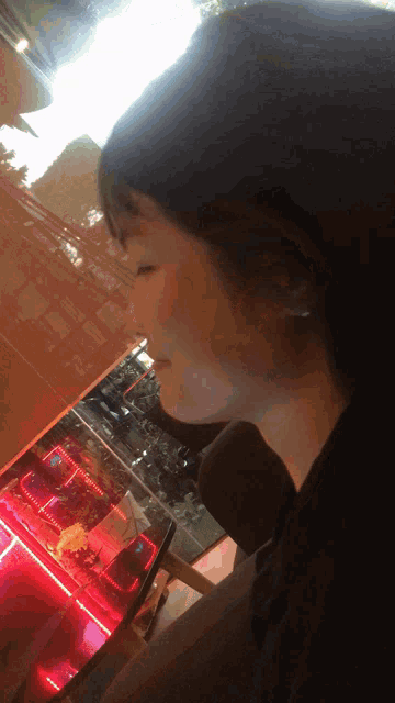 a woman is sitting in front of a red lighted display case