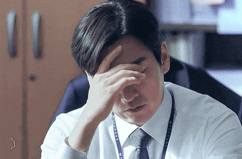 a man in a white shirt and tie is covering his face