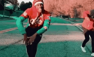 a man in a red shirt and green sleeves is dancing on a street .