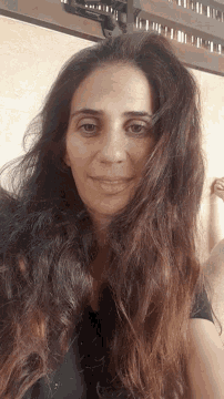 a woman with very long hair is smiling and looking at the camera