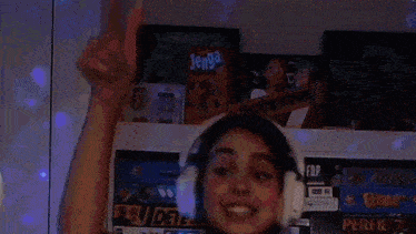 a woman wearing headphones is singing while standing in front of a shelf with jenga cards .