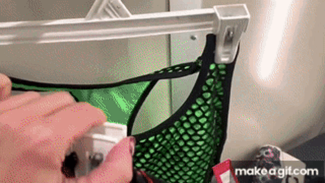 a person is spraying a green tank top with a white spray bottle .