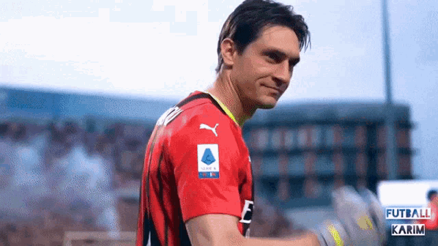a soccer player wearing a red jersey with a puma logo on the sleeve